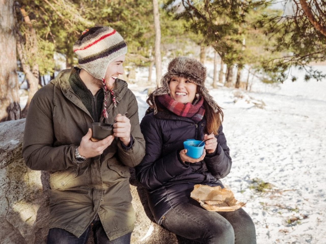 Молодая пара с удовольствием пьёт кофе из термоса на горке для катания на санках.