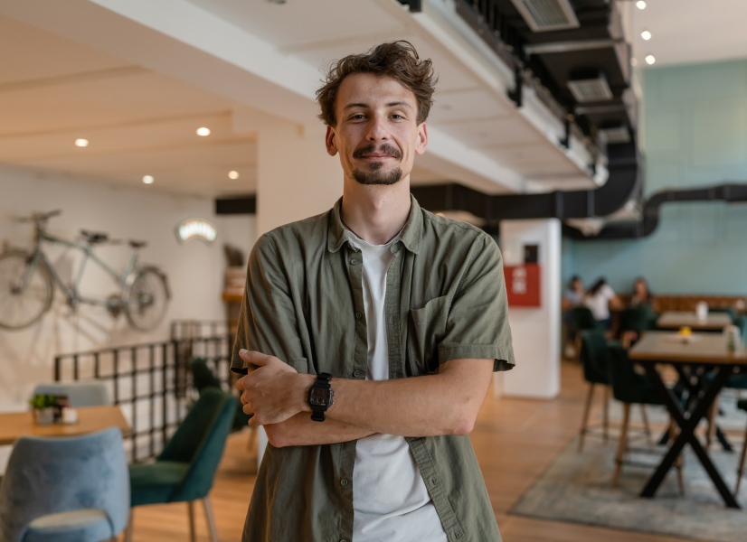 A man born in the 90s standing in a cafe.
