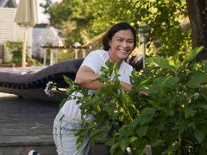 Rõõmus naine hoolitseb õuetaime eest.