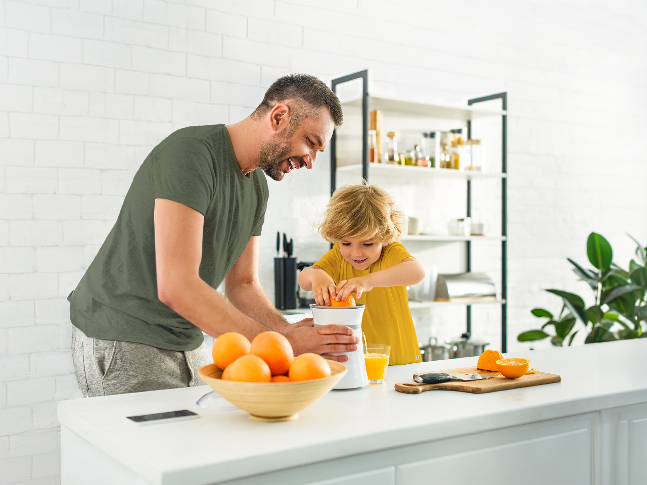 Father and son squeezing out orange juice from oranges.